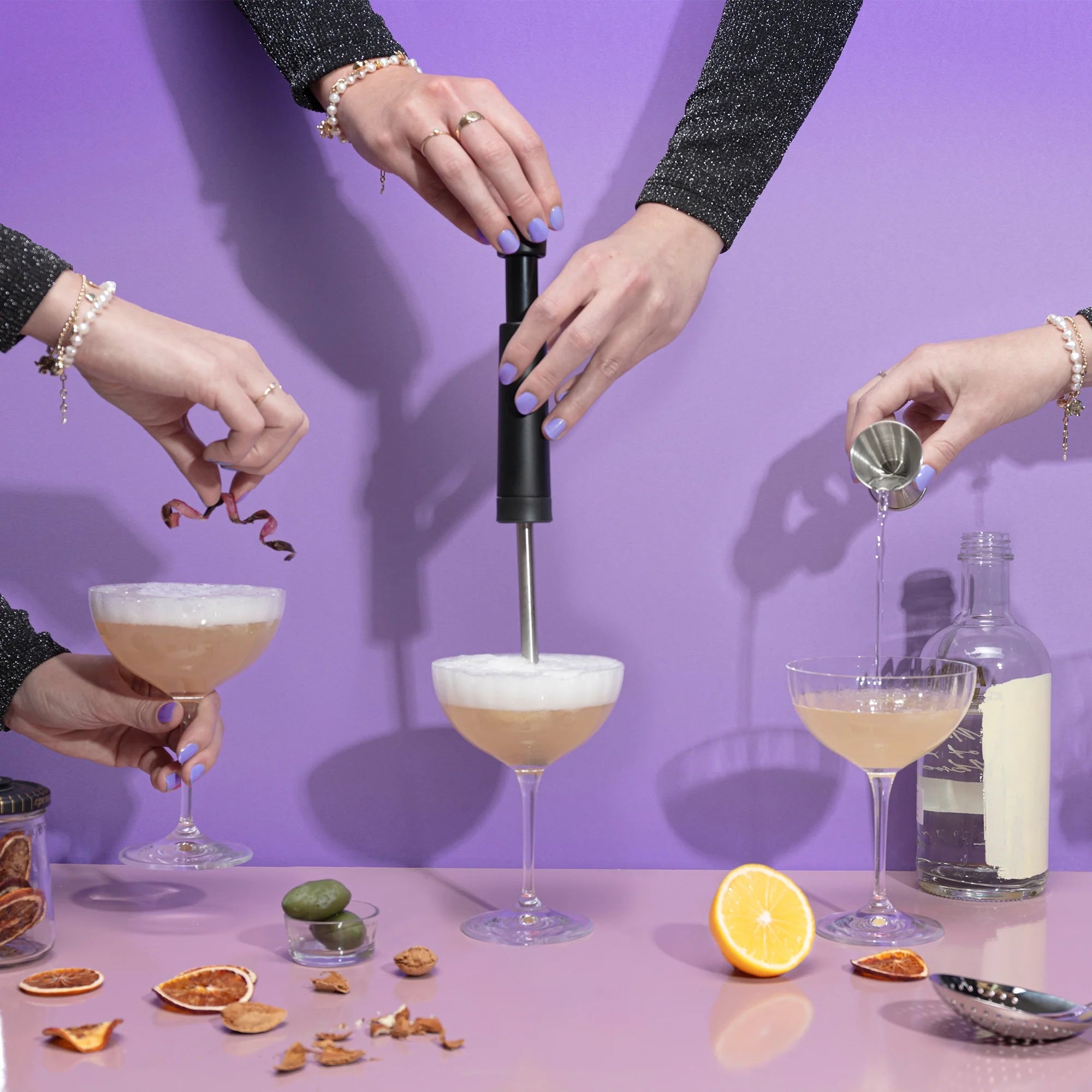 People preparing cocktails using the Airtender Cocktail Aerator with a purple background
