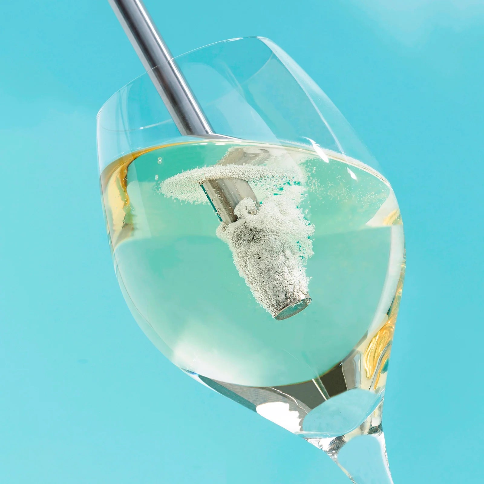 Close up of a wine glass with being aerated by the Airtender Wine Aerator on a light blue background