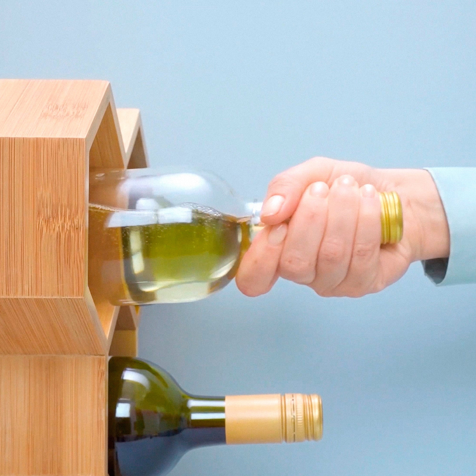Hand placing a vacuum sealed wine bottle horizontally in a wine rack